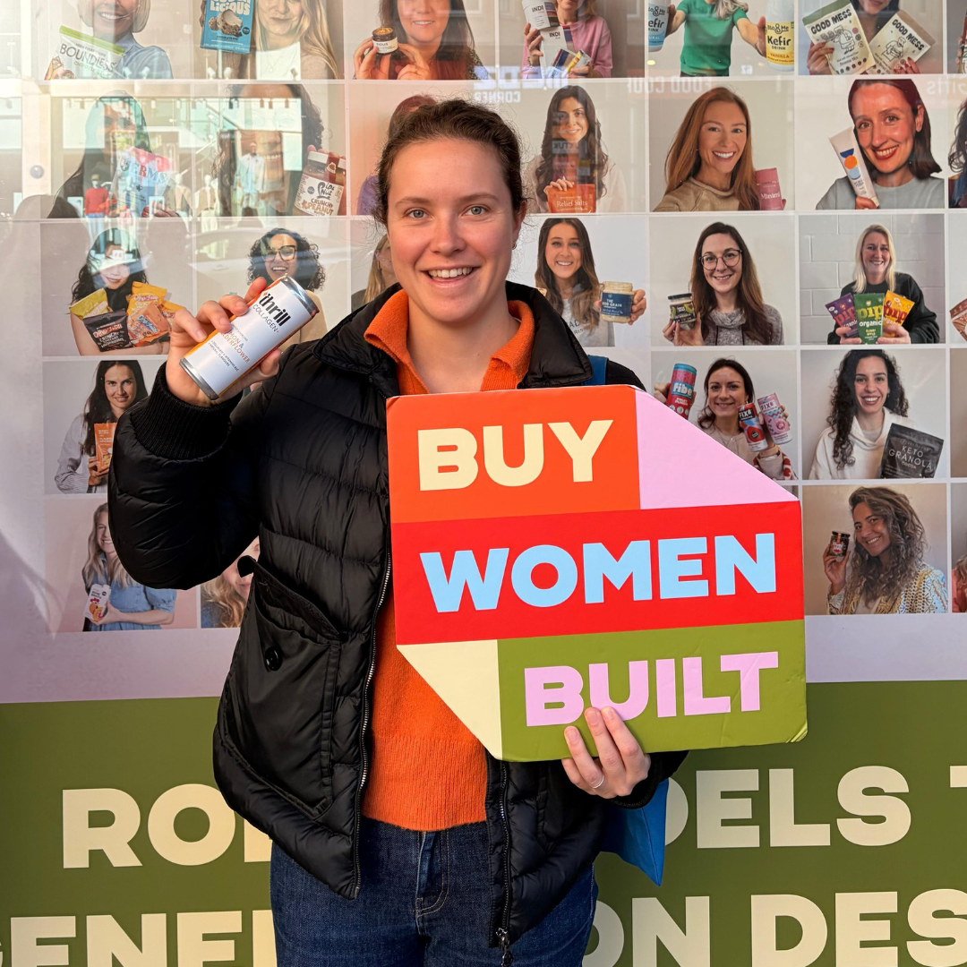 Laure Puissilieux holding a sign with 'BUY WOMEN BUILT' in front of wholefoods. 